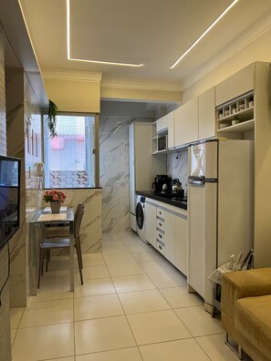 Une cuisine moderne avec un coin repas, un lave-linge et un réfrigérateur.