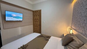 A hotel room with a bed, a television mounted on the wall, a wooden door, and a textured wall. - 106 - Modern 2-Bedroom Apartment (Belém)