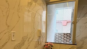 A room with a marble wall, a glass table, and a window with a view of a building. - 106 - Modern 2-Bedroom Apartment (Belém)