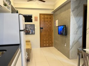 A modern kitchen with a refrigerator, a dining area with a table and chairs, a television mounted on the wall, and a wooden door. - 106 - Modern 2-Bedroom Apartment (Belém)