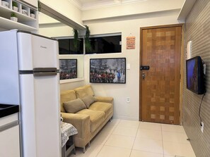 A compact kitchen with a white refrigerator, a beige sofa, and a wooden door. - 106 - Modern 2-Bedroom Apartment (Belém)