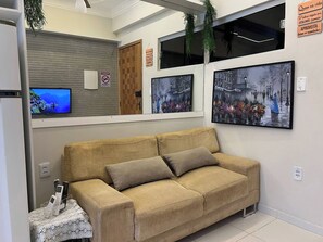 A waiting area with a sofa, a television, and framed pictures on the wall. - 106 - Modern 2-Bedroom Apartment (Belém)