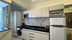 A modern kitchen with white cabinetry, a black countertop, a built-in microwave, a gas stove, and a refrigerator. - 106 - Modern 2-Bedroom Apartment (Belém)