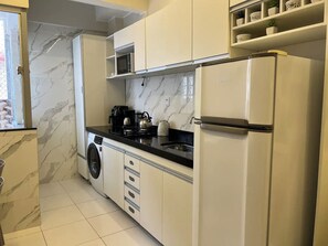 A compact kitchen with a washing machine, a microwave, and a refrigerator. - 106 - Modern 2-Bedroom Apartment (Belém)