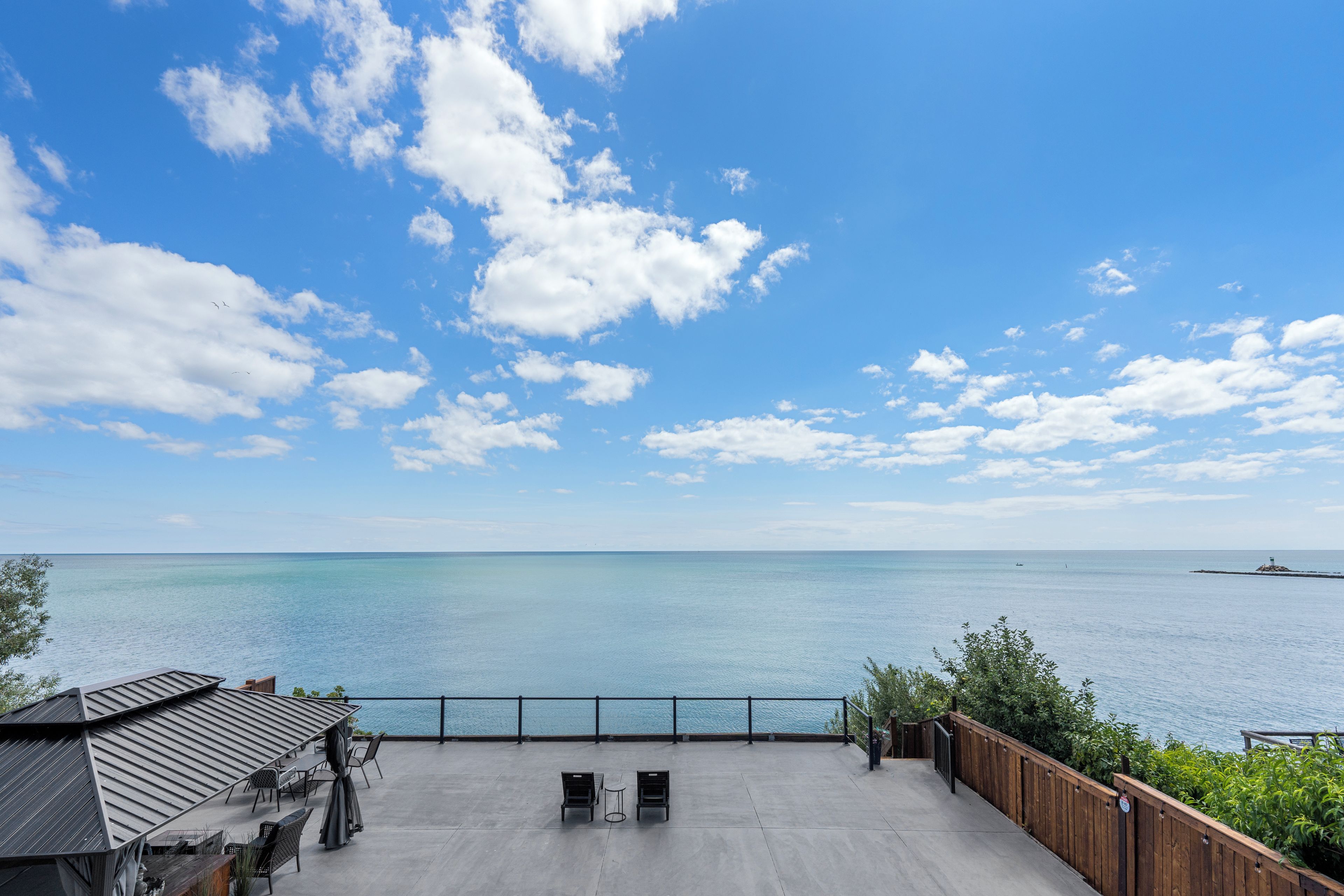 A patio with outdoor seating overlooking a calm sea.