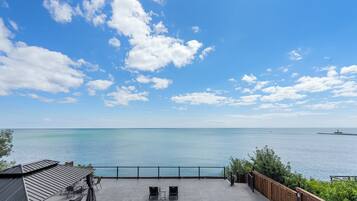 A patio with outdoor seating overlooking a calm sea.