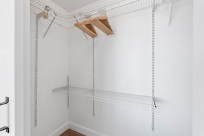A white closet with metal shelving and wooden hangers.
