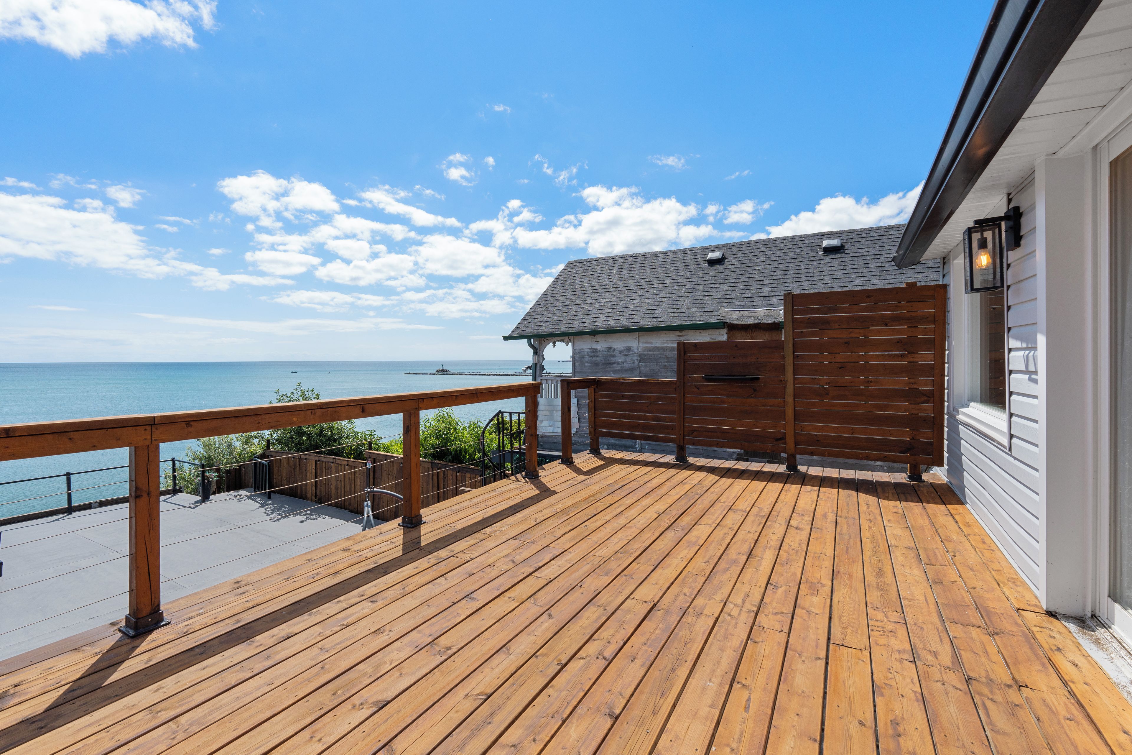 A wooden deck with a railing overlooking a body of water.