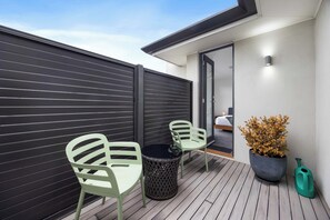 A patio with two chairs, a table, a potted plant, and a water jug. - The Onka Contemporary Escape by the Coast (Port Noarlunga)