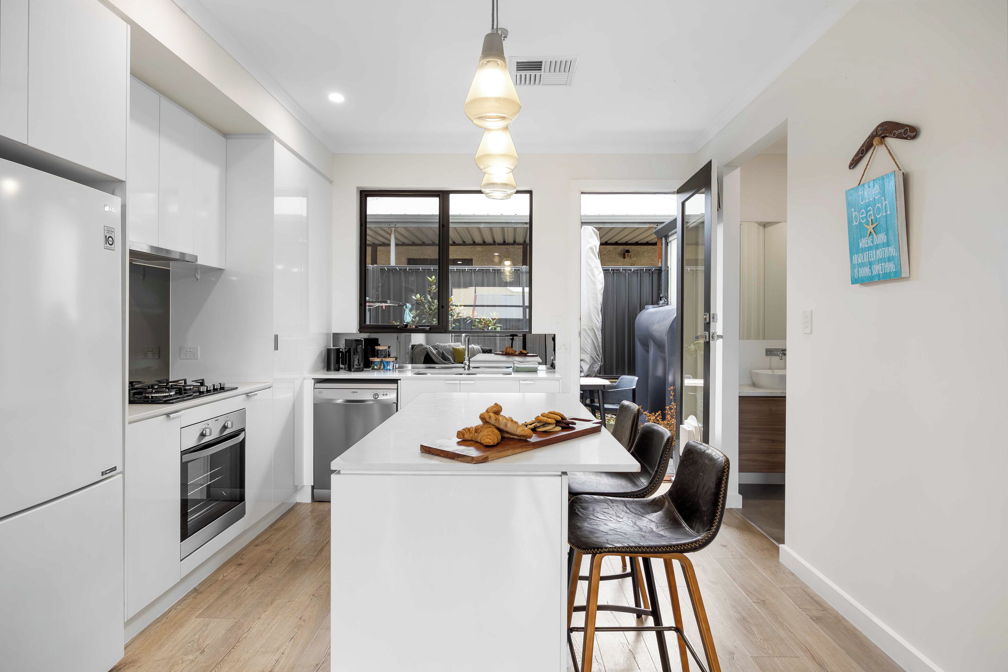 A modern kitchen with white cabinetry, a central island, and a hanging light fixture.
