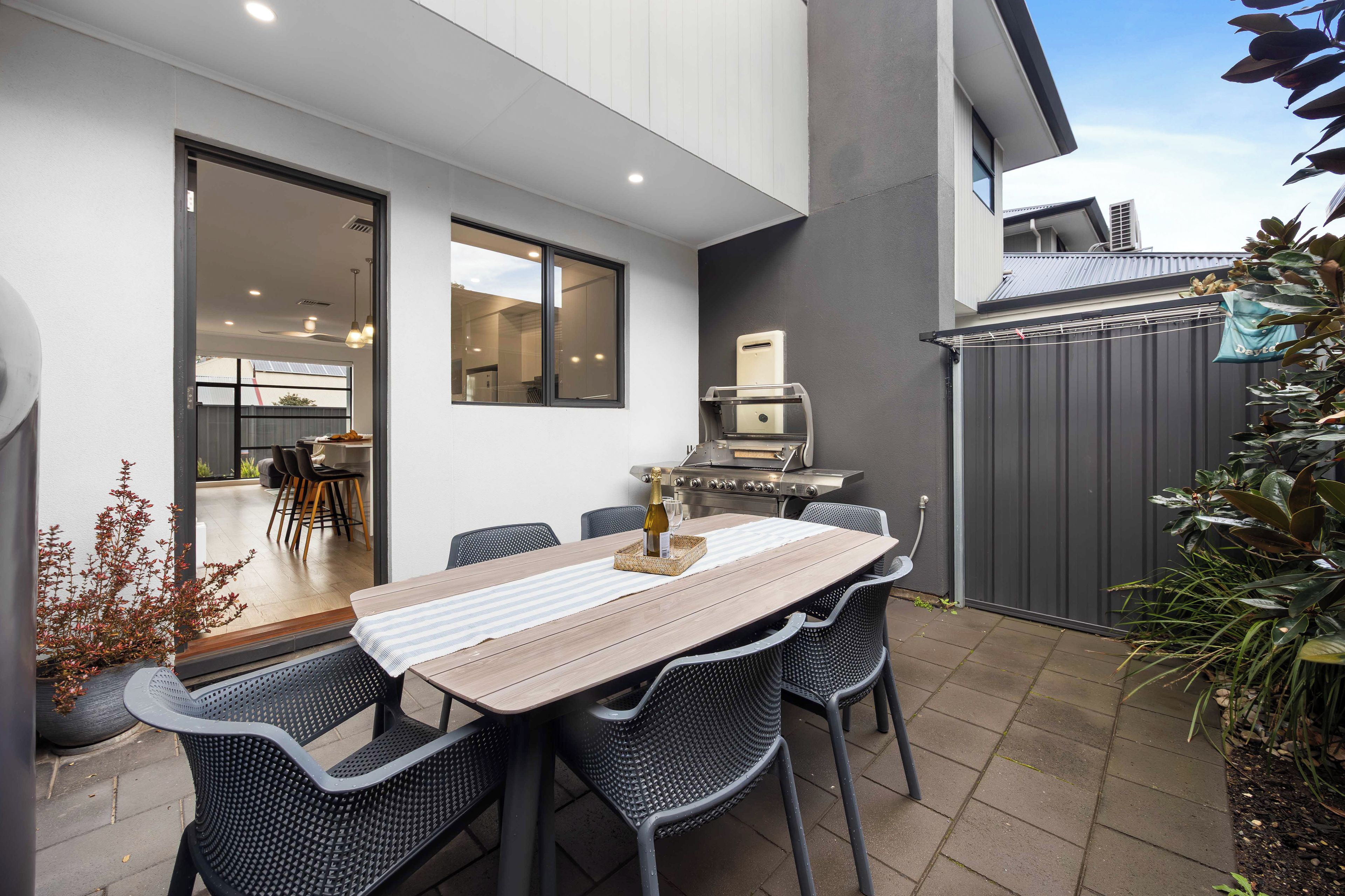 An outdoor patio with a dining table, chairs, and a barbecue grill.