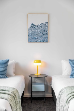 A hotel room with two beds, a small table with a lamp, and a framed artwork on the wall. - The Onka Contemporary Escape by the Coast (Port Noarlunga)