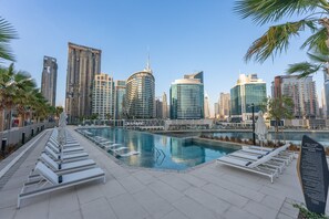 Ein Swimmingpool mit Liegestühlen und einer Stadtkulisse im Hintergrund.