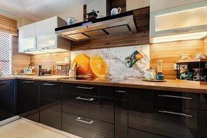 Une cuisine moderne avec des meubles de couleur sombre, un pare-feu en marbre et un plan de travail en bois.