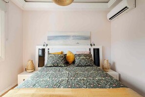 Une chambre à coucher avec un lit, un tableau accroché au-dessus du lit et un appareil de climatisation fixé au mur.