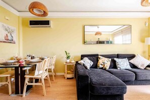 A living room with a dark sofa, a dining table with chairs, a small side table with a plant, and a large mirror on the wall. - A vacation home where you can feel right at home... (Las chafiras)