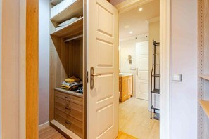 A walk-in closet with wooden shelving and drawers, leading to a bathroom with a shower and a toilet. - A vacation home where you can feel right at home... (Las chafiras)