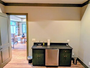 A kitchen with a double sink, dark cabinets, and a stainless steel refrigerator.