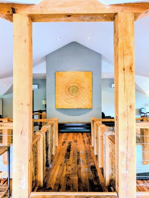 A wooden staircase leading to a room with a large abstract painting on the wall.