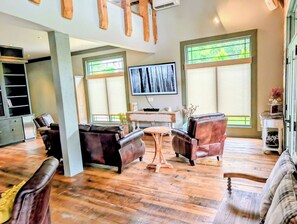 Un salon spacieux doté d’un grand téléviseur, d’un plancher en bois et d’une cheminée.