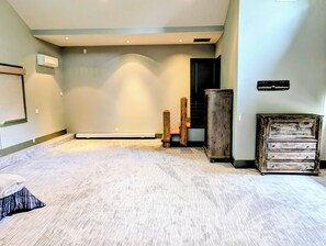 A room with a carpeted floor, a wooden cabinet, and a staircase.