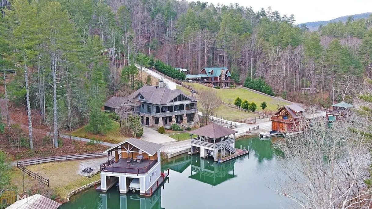 A lakeside property with multiple buildings, docks, and a boat.
