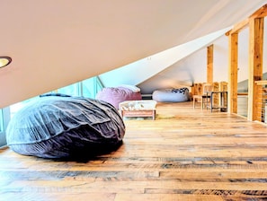 A loft-style room with a sloped ceiling, wooden flooring, and a large bean bag chair.