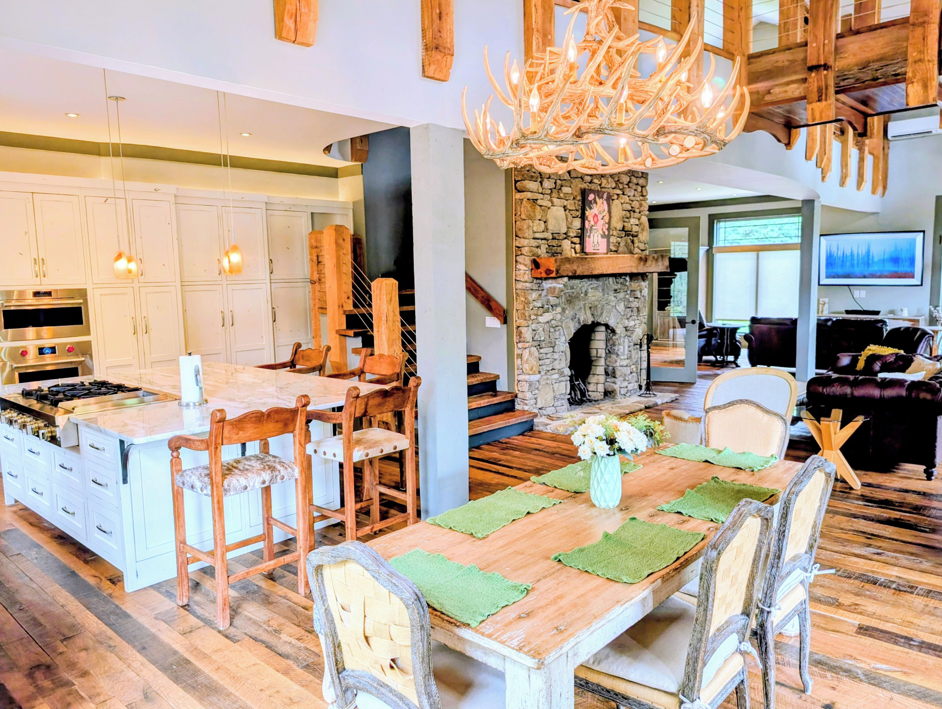 A spacious living area with a fireplace, wooden flooring, and a dining table with chairs.