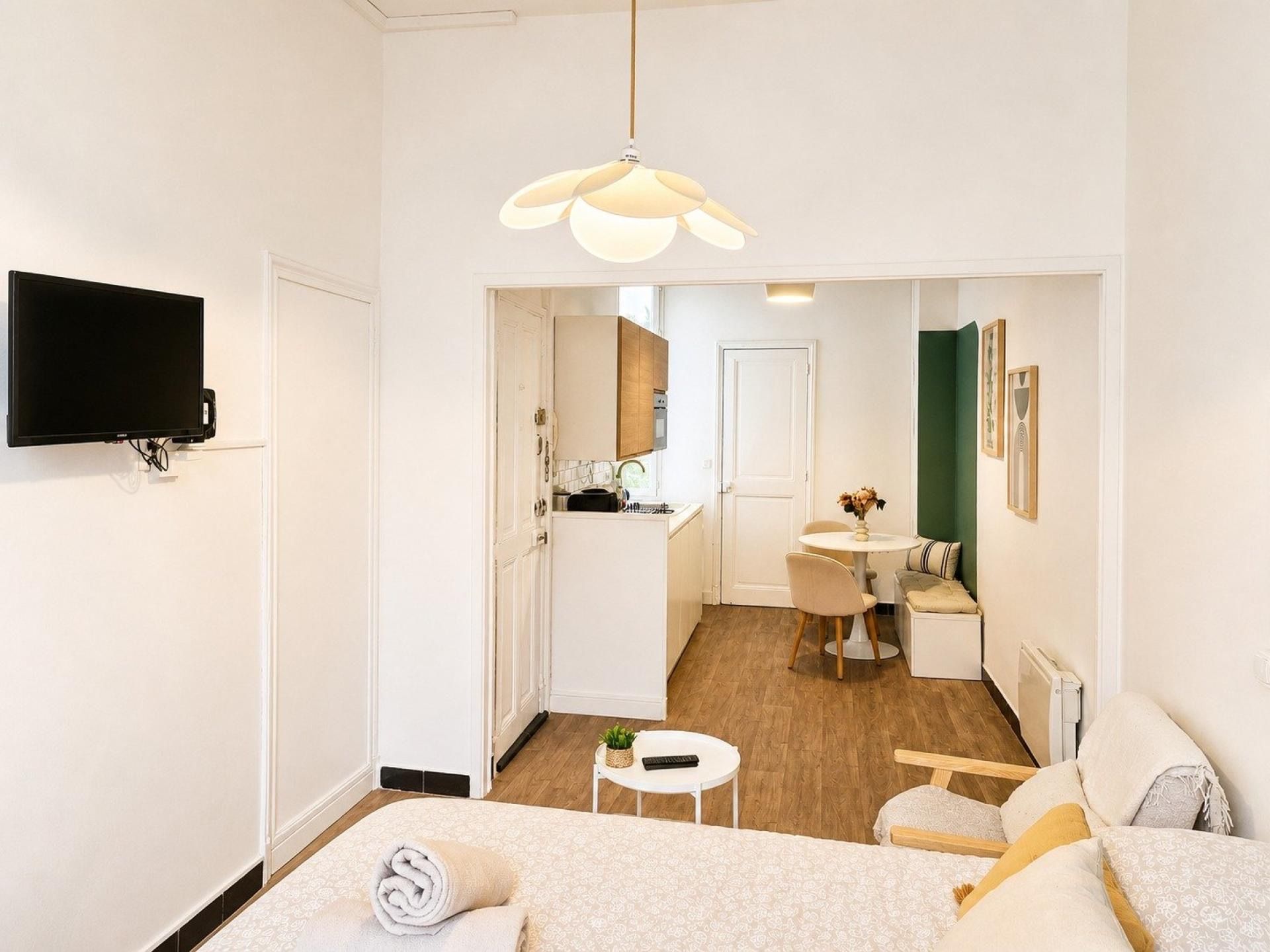 Ein modernes Hotelzimmer mit Bett, Fernseher, Essbereich und einer Küche im Hintergrund.