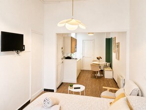 Ein modernes Hotelzimmer mit Bett, Fernseher, Essbereich und einer Küche im Hintergrund.