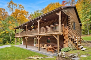 A log cabin with a balcony, outdoor seating, and a stone pathway. - Private Cabin Retreat | near Stratton & Mt. Snow (Jamaica)
