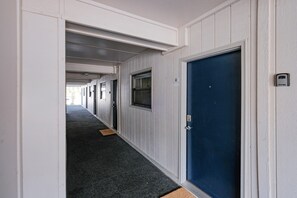 Un passadís amb portes a banda i banda, un sòl amb moqueta i una porta blava al final.
