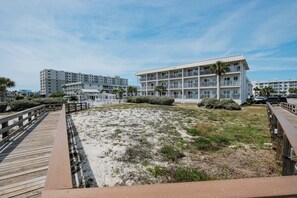 A beachfront hotel with a boardwalk leading to the property, surrounded by sand and sparse vegetation. - 🌊 Coastal Beachfront Escape – Relaxed Gulf Views & Resort Living (Gulf Shores)