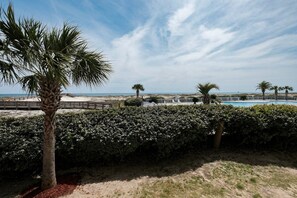 A beachfront property with a swimming pool, palm trees, and a sandy beach. - 🌊 Coastal Beachfront Escape – Relaxed Gulf Views & Resort Living (Gulf Shores)