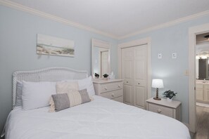 Ein Schlafzimmer mit Bett, Kommode, Spiegel und Nachttisch mit Lampe.