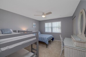 A bedroom with bunk beds, a desk, a chair, a large mirror, and a ceiling fan. - Pet Friendly Townhome Directly Across from the Beach in Quiet Ormond By the Sea (Ormond Beach)