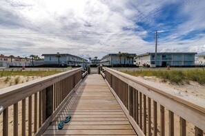 A wooden boardwalk leading to a row of beach houses with a clear sky above. - Pet Friendly Townhome Directly Across from the Beach in Quiet Ormond By the Sea (Ormond Beach)