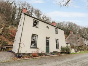 A two-story building with a green door, multiple windows, and a chimney. - Llys Gwaun (Fishguard)