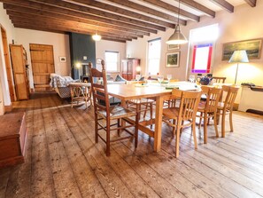A cozy room with a wooden dining table, chairs, and a fireplace. - Llys Gwaun (Fishguard)