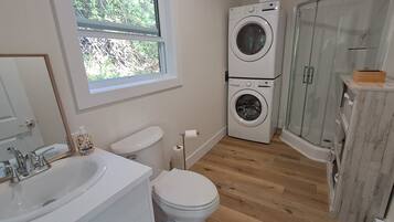 A bathroom with a sink, toilet, and a double washing machine.