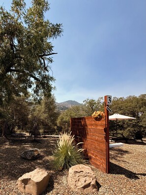 A wooden gate with a number sign, a picnic area with an umbrella, and a natural landscape with trees and hills in the background. - Luxury Camper Van Parking - 16 miles to Yosemite 5 miles to Bass Lake! #3 (Oakhurst)