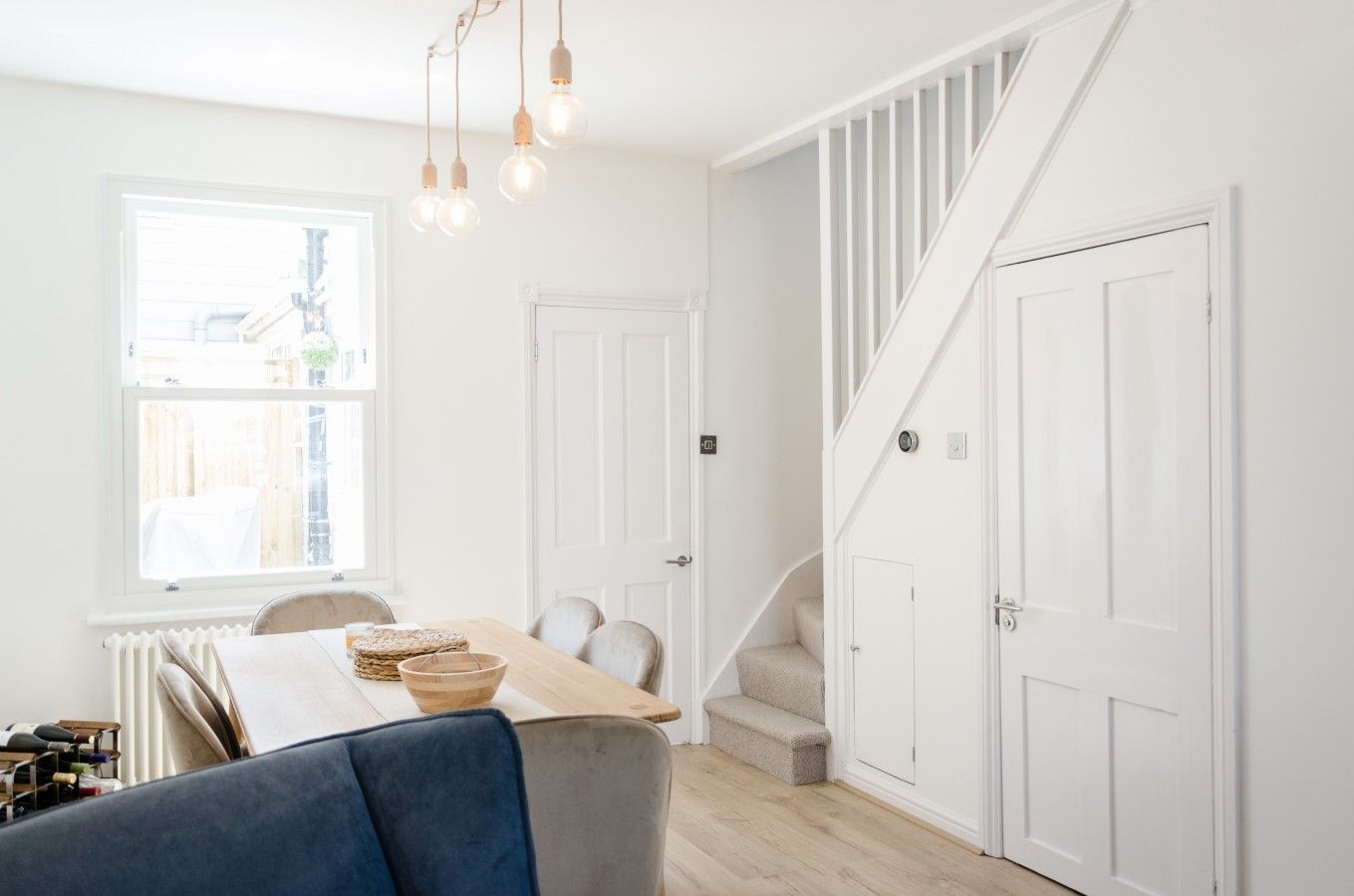 A bright room with a wooden table, chairs, and a staircase.