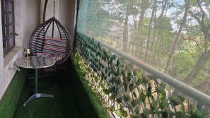 A balcony with a hanging chair, a small table with a glass, and a view of greenery through a mesh screen. - Kamakis,Ruiru Eastern bypass (Ruiru)