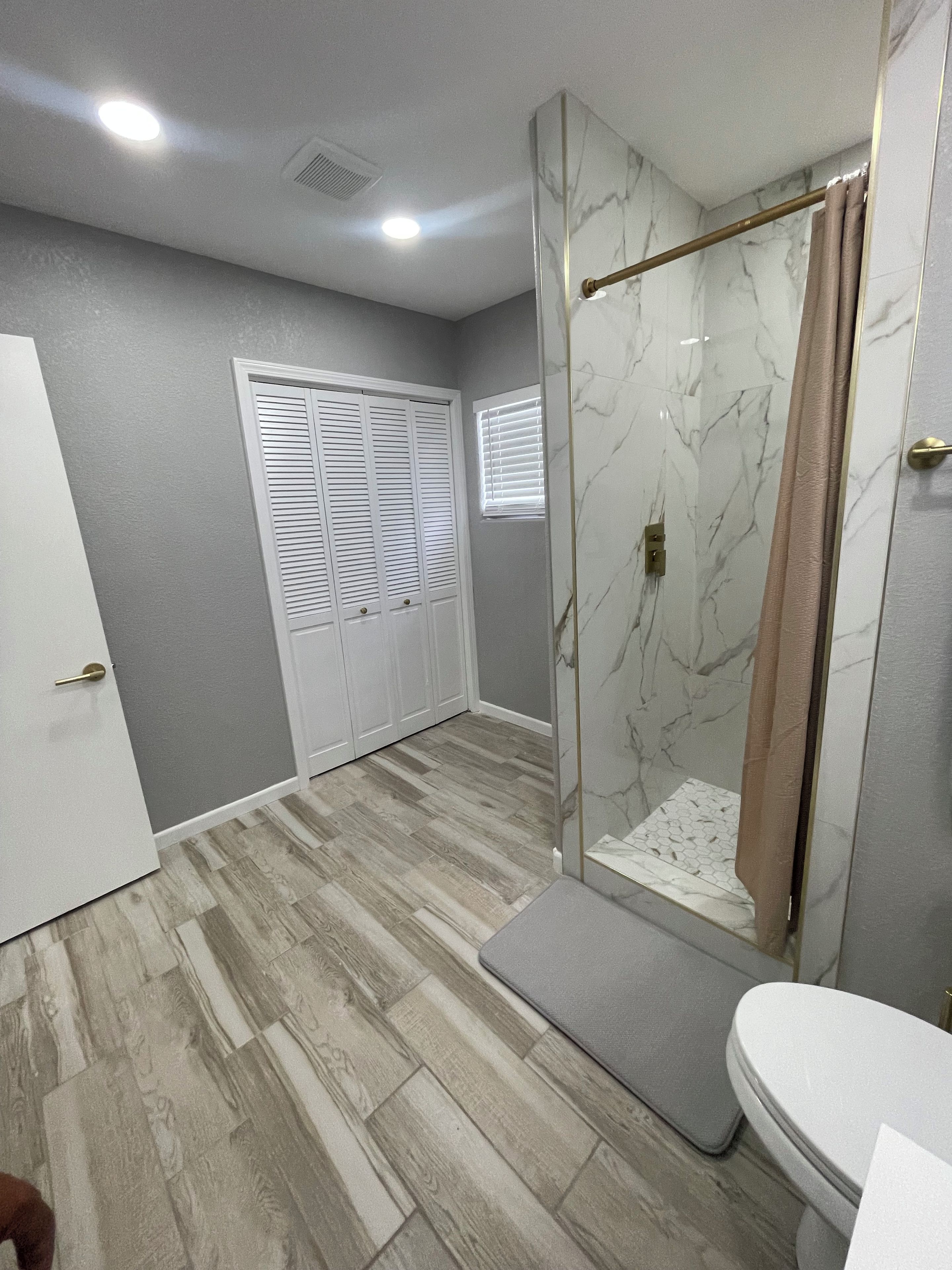 A bathroom with a shower, toilet, and a vanity.