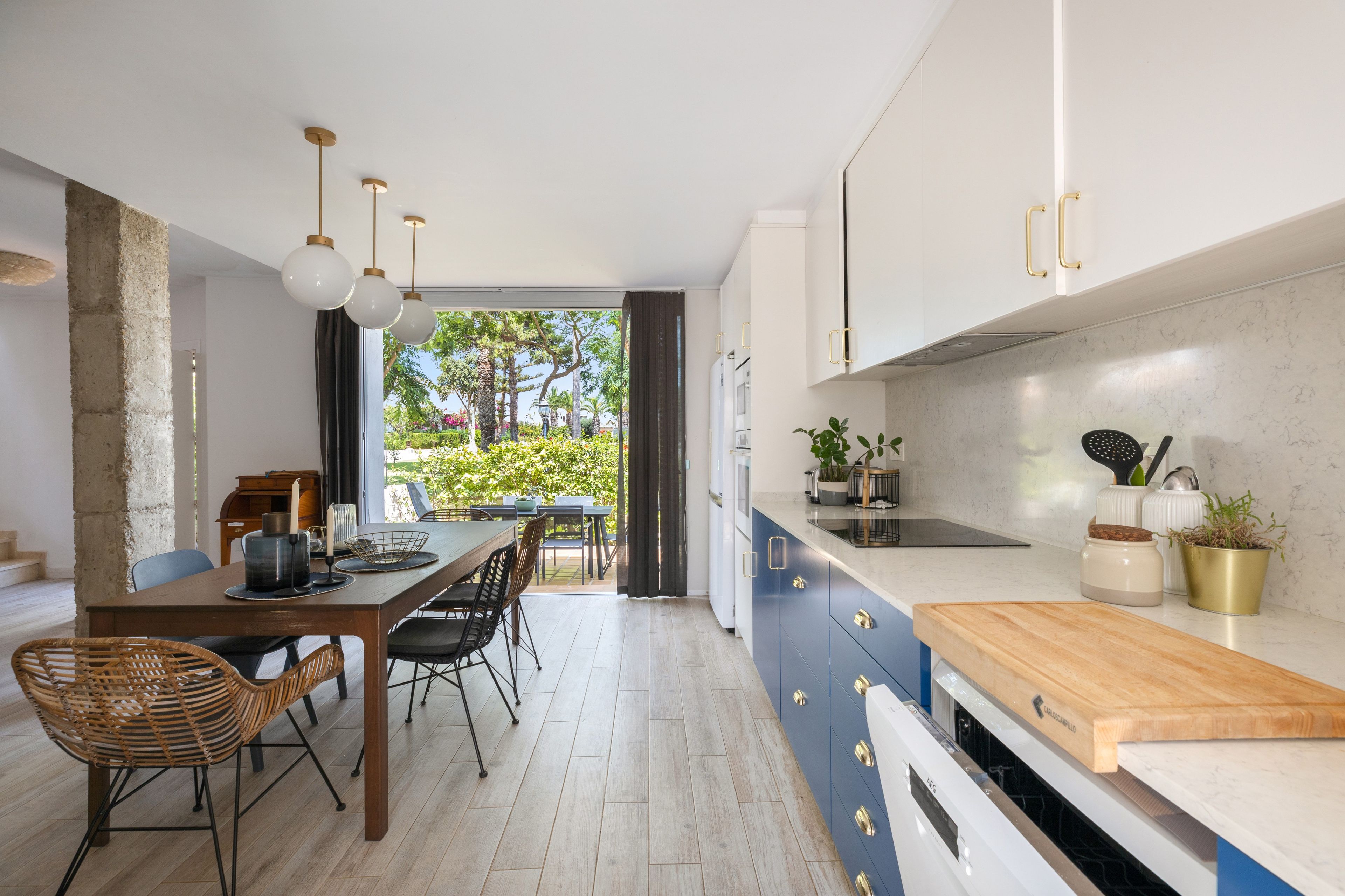 Una cocina moderna con comedor, que incluye una mesa de madera, sillas y vistas a un jardín por la ventana.