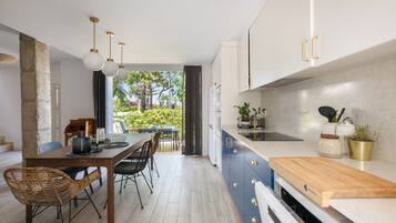 Una cocina moderna con comedor, que incluye una mesa de madera, sillas y vistas a un jardín por la ventana.