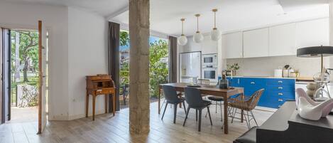 A spacious kitchen with modern appliances, a dining area with a wooden table and chairs, and a large open space with a concrete pillar.