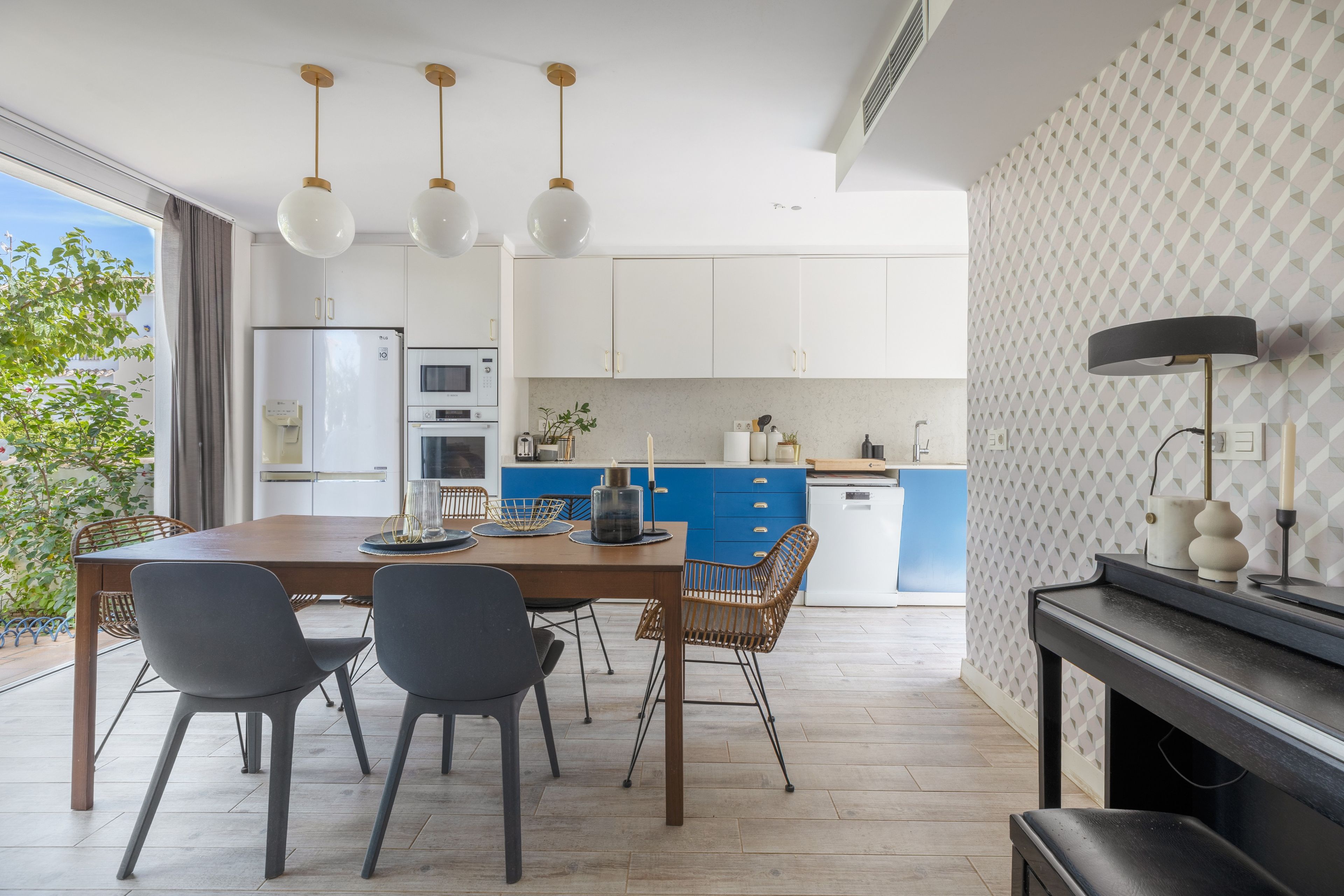 Eine moderne Küche mit weißen Schränken, einer blauen Arbeitsplatte und einem Essbereich mit einem Holztisch und Stühlen.