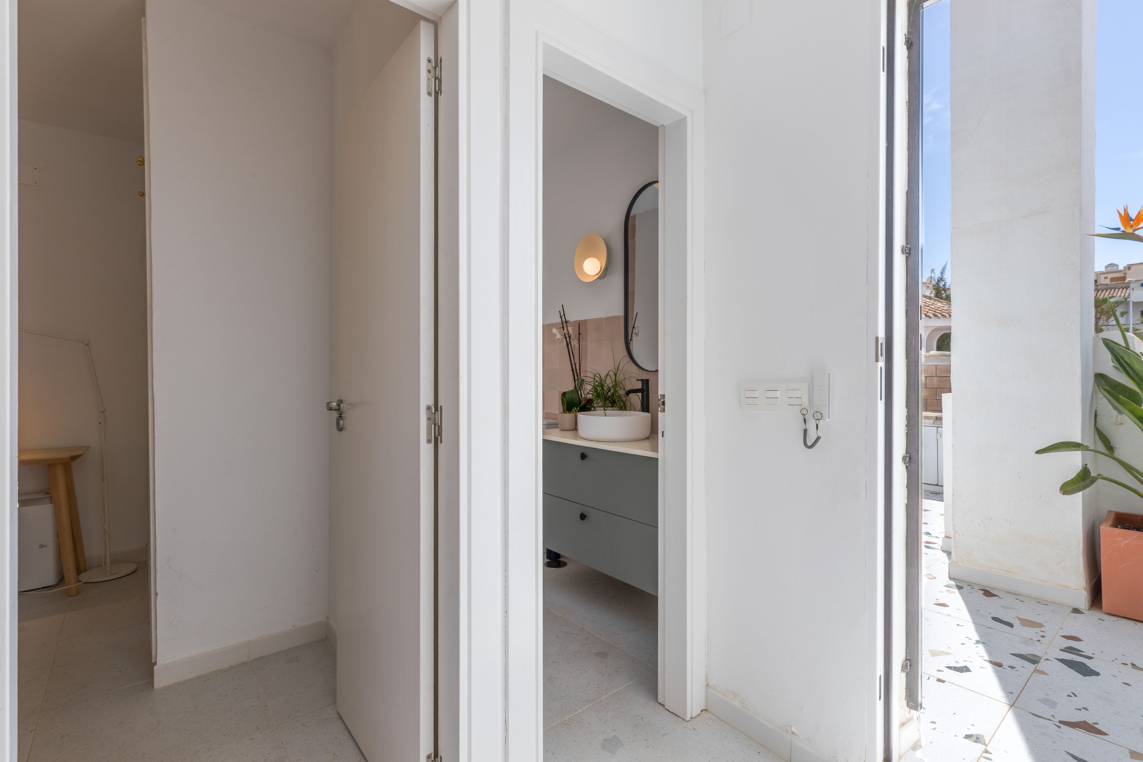 Une salle de bain avec un lavabo blanc, un miroir et une plante en pot.