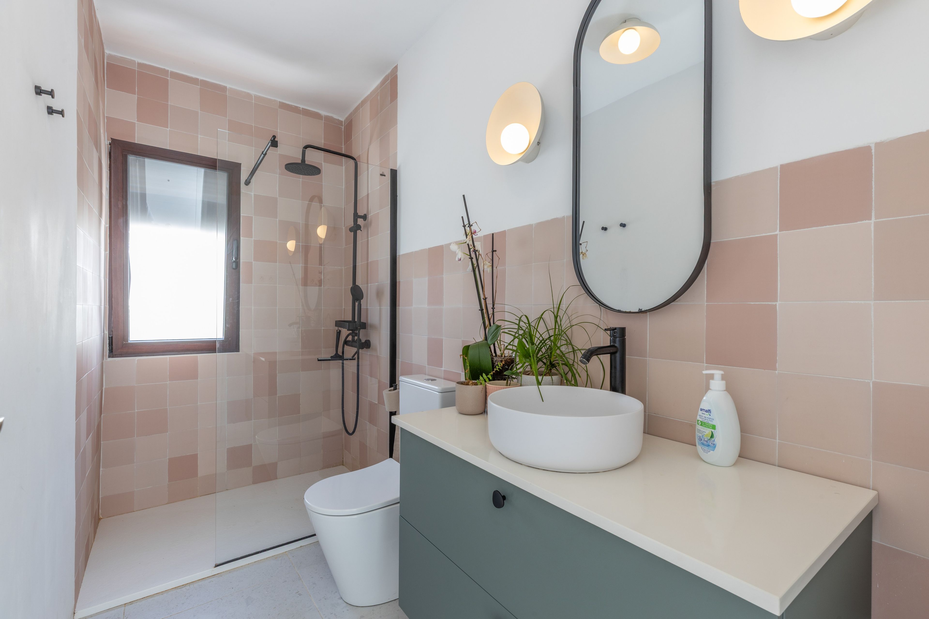 Een moderne badkamer met een inloopdouche, toilet, wastafel en spiegel.